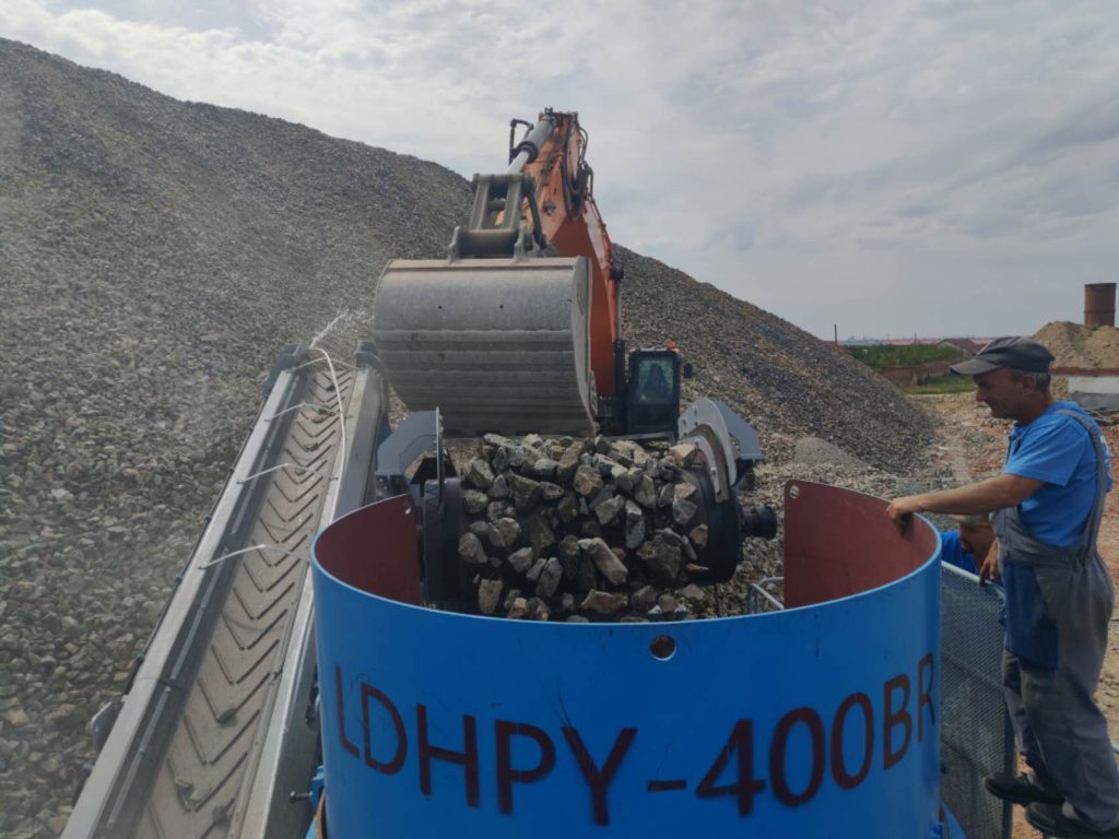 ldhpy400br-podacha-materiala-v-konusnuyu-drobilku.jpg Подача материала в гусеничную конусную дробилку LDHPY-400BR Подача материала в LDHPY-400BR Материал подается в загрузочный бункер гусеничной конусной дробилки LDHPY-400BR на европейском объекте. Гусеничная конусная дробилка LDHPY-400BR принимает материал через загрузочный бункер, обеспечивая непрерывную работу мобильной дробильной установки на объекте по производству щебня.